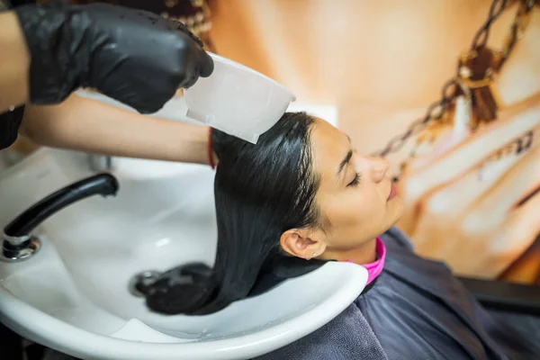 female client washes hair in salon, professional hairdresser washes head of female client with water and shampoo treatment, hairstyle beauty hair care, fashion service.