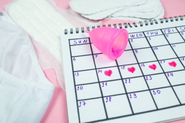 calendar photo, underwear, menstrual cup, sanitary napkins on isolated pastel pink background. The concept of menstruation, women's creative days.