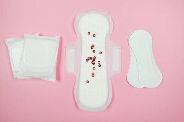 Photo from above of a panty liner on an isolated pastel pink background.