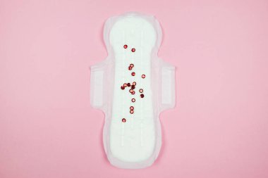Top view photo of panty liner with confetti on isolated pastel pink background