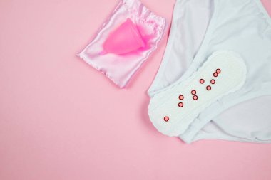 panties, pads, menstrual cup on a pink background. The concept of women's periods.