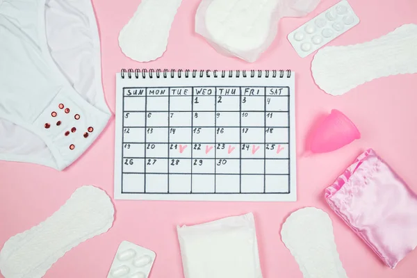 calendar photo, underwear, menstrual cup, sanitary napkins on isolated pastel pink background. The concept of menstruation, women\'s creative days.