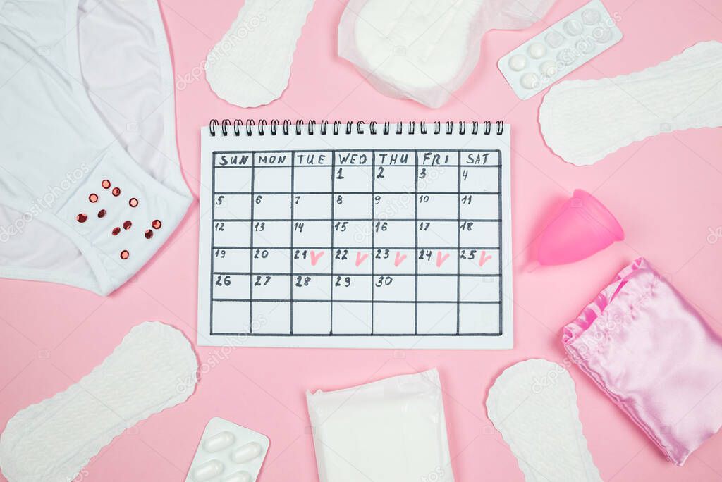 calendar photo, underwear, menstrual cup, sanitary napkins on isolated pastel pink background. The concept of menstruation, women's creative days.