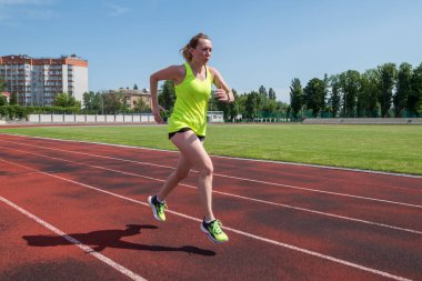 Sports woman runs in the stadium.