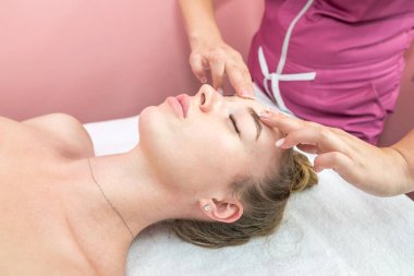 Beautiful girl doing facial massage in beauty clinic