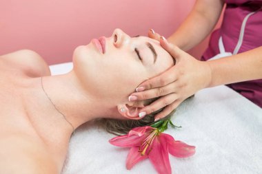 Beautiful girl doing facial massage in beauty clinic