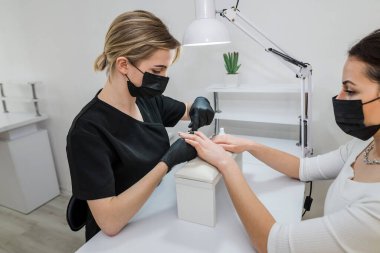 Closeup parmak tırnak bakım Güzellik Salonu manikür uzmanı tarafından. Manikürcü kütikül profesyonel kerpeten manikür ve pedikür için temizleyin.