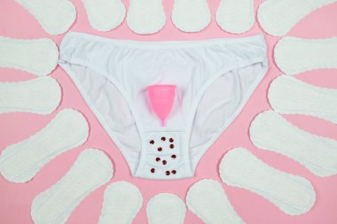panties, pads, menstrual cup on a pink background. The concept of women's periods.