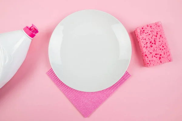 empty white sponge plate and dish detergent bottle on pink background. View from above.