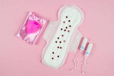 Pad, tampon and menstrual cup on a pink background. The concept of critical days, menstruation. Feminine hygiene on critical days