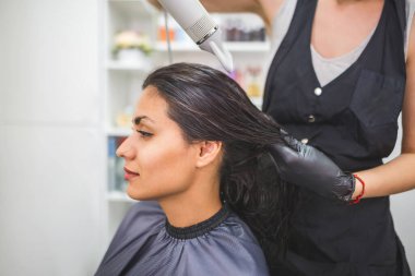Drying long dark hair with a hairdryer.professional hairdresser dries the hair of a client in the salon, hairstyle beauty hair care, fashion service.