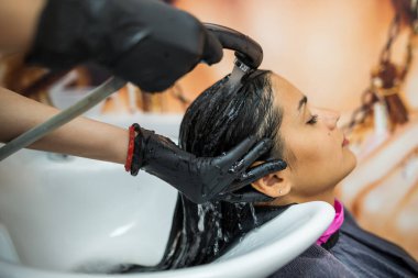 female client washes hair in salon, professional hairdresser washes head of female client with water and shampoo treatment, hairstyle beauty hair care, fashion service.