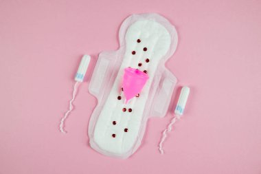 Pad, tampon and menstrual cup on a pink background. The concept of critical days, menstruation. Feminine hygiene on critical days