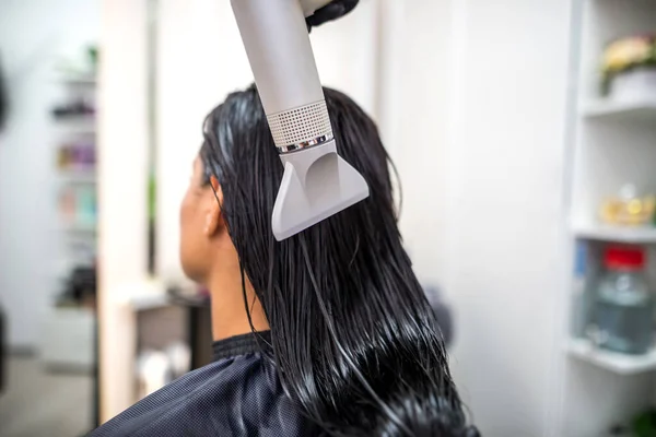 Drying long dark hair with a hairdryer.professional hairdresser dries the hair of a client in the salon, hairstyle beauty hair care, fashion service.