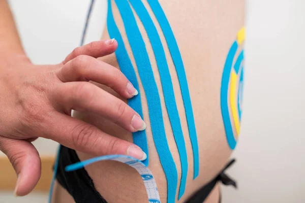理学療法士は 医師室の若い成人運動選手の腹部側に接着剤弾性治療テープを適用します 傷害リハビリテーションと医療 — ストック写真