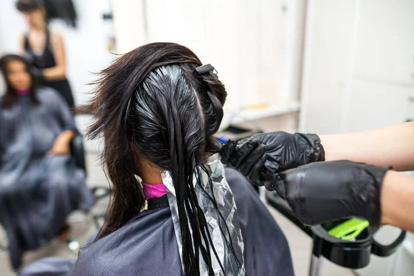 The hairdresser applies professional liquid keratin to the client\'s hair. A girl does keratin hair strengthening in a beauty salon. Hair care.