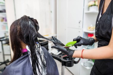 Kuaför müşterinin saçına profesyonel sıvı keratin uygular. Bir kız kuaförde keratin saç güçlendiriyor. Saç bakımı.