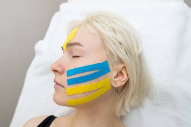 Yüz bandı, kırışıklık önleyici kozmetoloji bandıyla bir kızın yüzünün yakın çekimi. Yüzün estetik bandı. Kırışıklıkları azaltmak için yaşlanmayı önleyici bir yöntem.