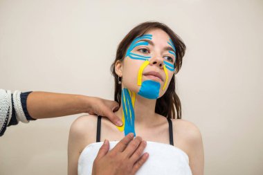 Kinesio kayıt yapıyor. Fizyoterapist hastanın boynuna kineziyoloji bandı yapıştırıyor. Travma sonrası rehabilitasyon, spor fizyoterapisi, boyun sıkma..