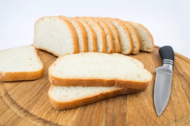 Beyaz arka planda dilimlenmiş ekmek ve bıçak. Beyaz ekmek dilimleri. Beyaz arkaplanda baton.