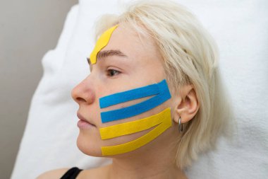 Yüz bandı, kırışıklık önleyici kozmetoloji bandıyla bir kızın yüzünün yakın çekimi. Yüzün estetik bandı. Kırışıklıkları azaltmak için yaşlanmayı önleyici bir yöntem.