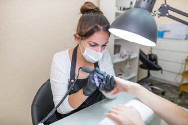 Çivi bakımı konsepti. Manikürcü, kuaförde müşterisi olan bir kıza manikür yapıyor..