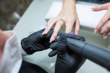 Çivi bakımı konsepti. Manikürcü, kuaförde müşterisi olan bir kıza manikür yapıyor..