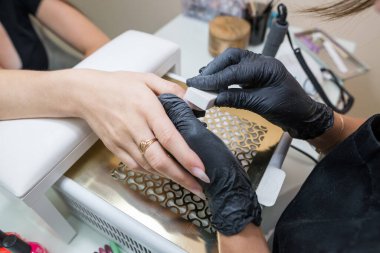 Çivi bakımı konsepti. Manikürcü, kuaförde müşterisi olan bir kıza manikür yapıyor..