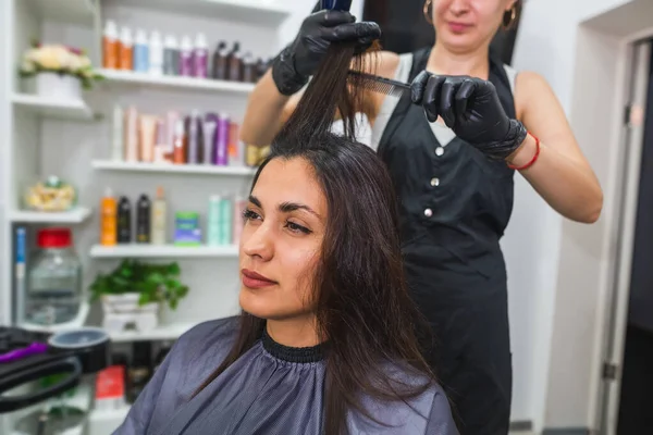 hair care in a beauty salon, a woman sitting in a chair makes procedures with her hair. Hair keratin process. Mask, straightening, lamination of women\'s hair