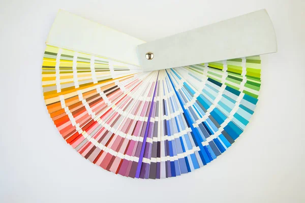 Color guide close up. Assortment of colors for design. Colors palette fan on white concrete wall background. Graphic designer chooses colors from the color palette guide. Coloured swatches catalogue
