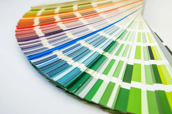 Color guide close up. Assortment of colors for design. Colors palette fan on white concrete wall background. Graphic designer chooses colors from the color palette guide. Coloured swatches catalogue