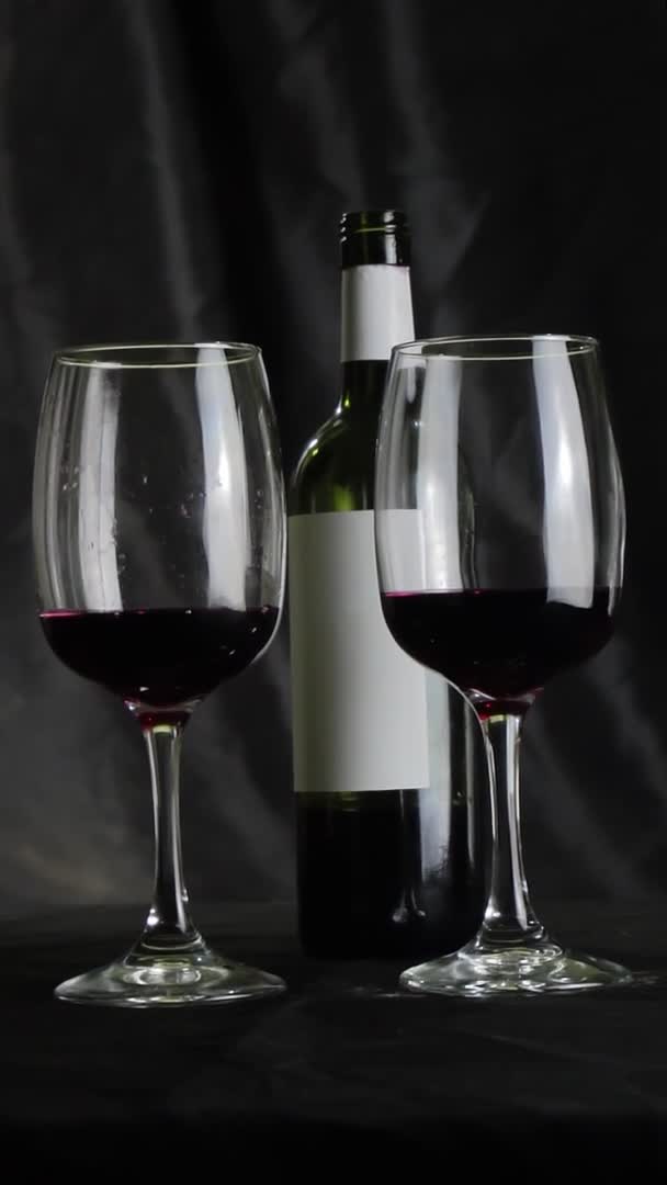 Glass of red wine and a bottle on a dark background. Slow motion — Stock Video