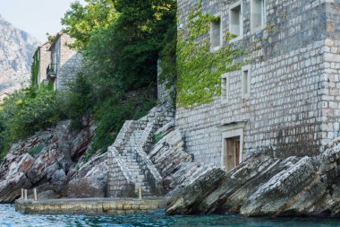 Karadağ, Avrupa, Adriyatik Denizi ve dağ yakınlarındaki Sveti-Stefan adasının güzel manzarası, rıhtım merdivenleri