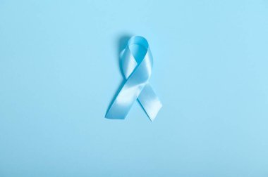 Dünya Diyabet Günü Farkındalık Konsepti. Mavi saten bir kurdelenin düz yatışı, sembolik yay rengi mavi renkli arka planda diyabet gününde farkındalığı artırıyor..