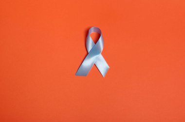 Mavi saten bir kurdelenin düz yatışı, 14 Kasım 'da reklam için fotokopi alanı olan turuncu arka planda diyabet günündeki farkındalığı artıran sembolik yay rengi. Dünya Diyabet Gündüz Farkındalığı.