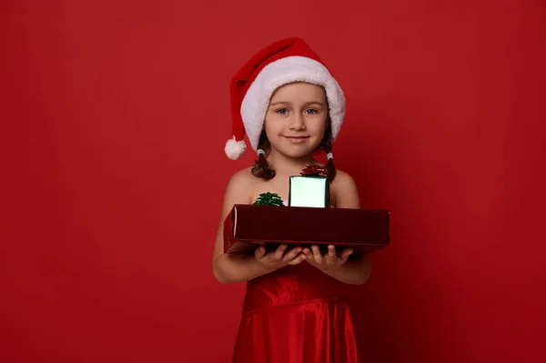 Nettes Kleines Mädchen Weihnachtsmannkostüm Mit Geschenken Auf Den Händen Lächelt — Stockfoto