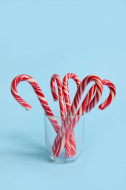 Mavi zemin üzerinde şeffaf cam üzerinde noel lolipopları ve reklam için fotokopi alanı olan güzel minimalist basit kompozisyon