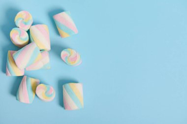 Mavi pastel arka planda renkli, tatlı marşmelovlar. Reklam için fotokopi alanı var. Düz yatay minimalist bileşim