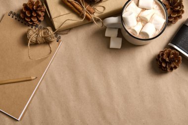 Hüner ambalajı kağıdında kesilmiş Noel hediyesi, iple bağlanmış tarçın, çam kozalakları, klasik kamera, kakaolu not defteri ve fotokopi alanı arkaplanlı marşmelov.