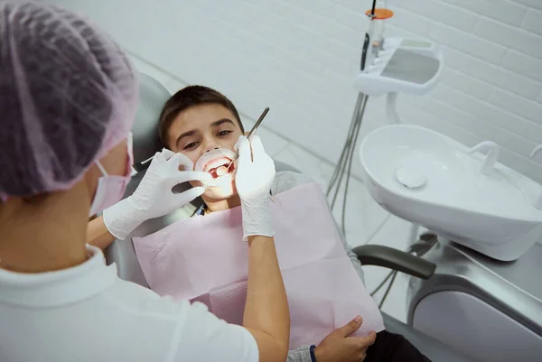 儿科牙医治疗儿童牙齿的俯视图 现代牙科诊所牙科预约时张嘴张颊的小学生近视 — 图库照片