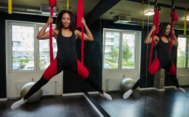 Bir stüdyoda hava sineği yogası esneme egzersizleri yapan oldukça genç Afrikalı kadınlara uyuyor. Spor ve sağlıklı yaşam tarzı kavramı