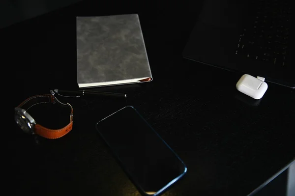 オフィスの付属品 ラップトップ ボックス上のイヤホン 携帯電話 グレーノートパッドの高い角度ビュー木製の机の上に — ストック写真