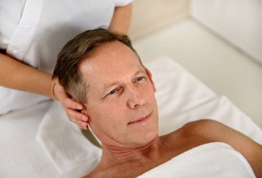 Yakışıklı, olgun Avrupalı bir adamın, sağlık merkezindeki kafa ve boyun masajı için profesyonel terapi görmesi.