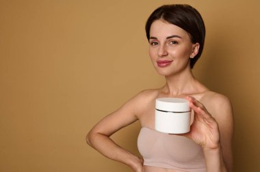 Stüdyoda, bej iç çamaşırlı, temiz ve sağlıklı bir cilde sahip güzel bir kadının bej renkli arka planda fotokopi reklamlarıyla poz verdiği bir fotoğraf çekimi. Deri ve vücut bakımı kavramı