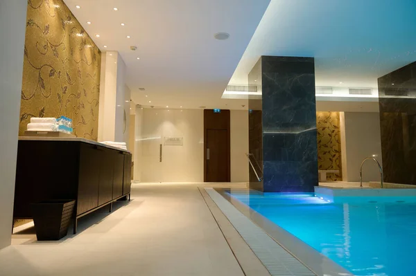 Luxury modern interior of the spa and wellness center with the thermal pool with underwater lighting and a waterfall.