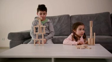 Birlikte masa oyunu oynayan sevimli Kafkas Tepesi. Tahta tuğlaları olan yakışıklı okul çocuğu, kanepede, kulesi yıkıldığında üzülen kız kardeşinin yanında oturuyor.