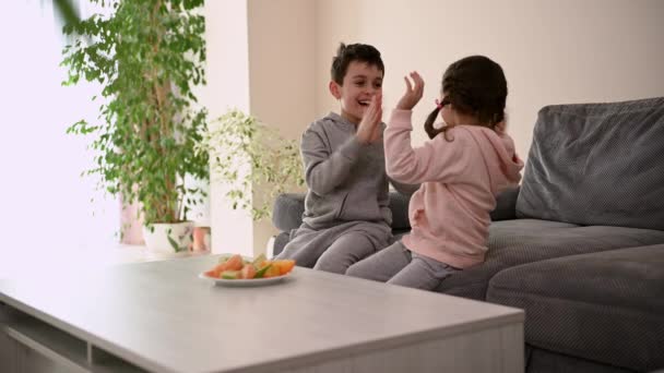 可爱的白人学龄儿童 兄弟姐妹 在家里客厅的沙发上玩耍 在家里享受周末 — 图库视频影像
