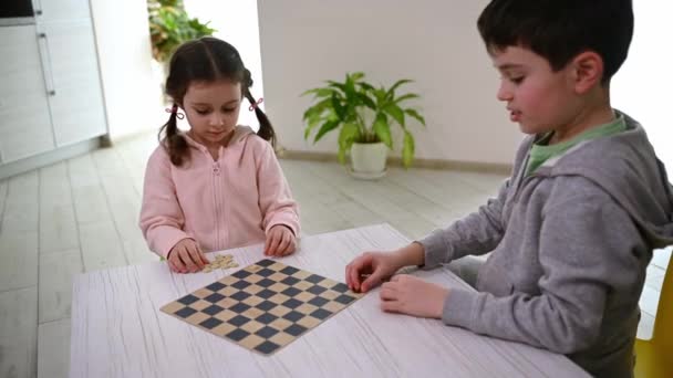 可爱的小女孩喜欢和哥哥玩智力棋盘游戏 把棋子放在棋盘上 逻辑发展 智能休闲 娱乐及智能业余爱好概念 — 图库视频影像