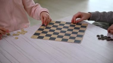 Satranç tahtasına dama taşlarını yerleştiren ve düzenleyen çocukların yakın plan fotoğrafları. Mantık geliştirme, entellektüel masa oyunları, eğitim, konsantrasyon ve akıllı eğlence kavramı.