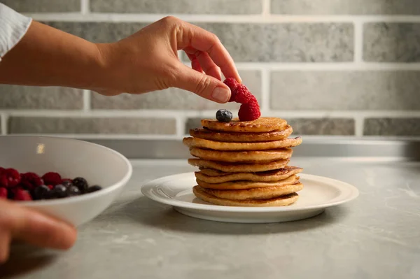 Tangan Koki Menempatkan Raspberry Atas Setumpuk Pancake Panggang Buatan Sendiri — Stok Foto
